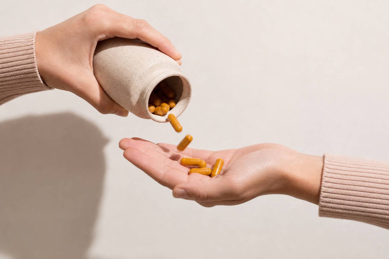 Main versant des gélules de curcuma dorées dans une paume ouverte