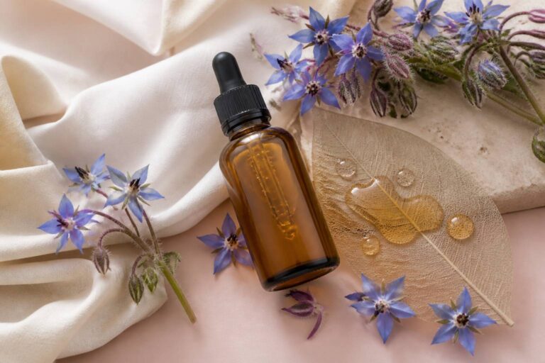 Flacon d'huile avec fleurs bleues de bourrache et gouttes dorées