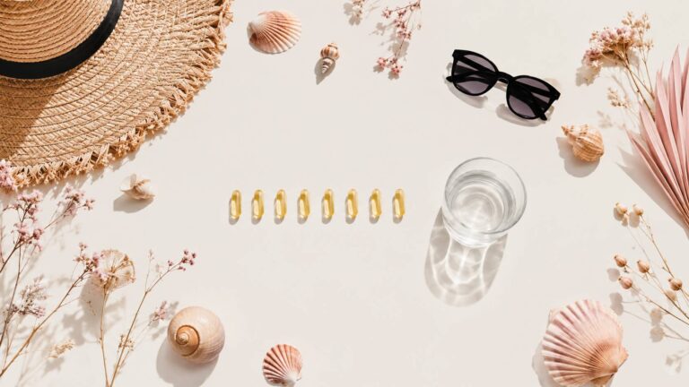 Flat-lay estival de gélules dorées avec chapeau de paille et lunettes de soleil
